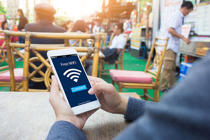 이미지: 야외에 앉아 전화를 들고 있는 남자; 전화 문자 메시지: Wi-Fi 기호 아이콘이 있는 무료 Wi-Fi